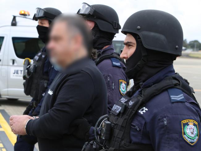 Police escort Sam Ibrahim to his plane to Perth on Thursday.