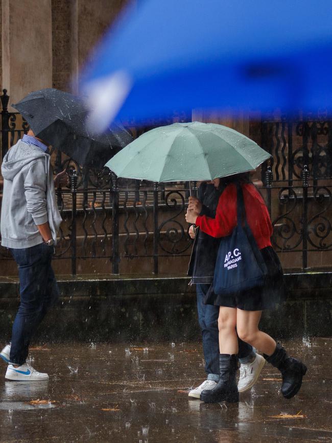 Pedestrians huddle under umbrellas as rain continues to drench the city. Picture: NewsWire / Max Mason-Hubers