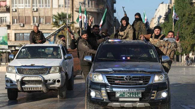 Anti-government fighters brandish their guns as they parade through the streets of Aleppo. Picture: AFP