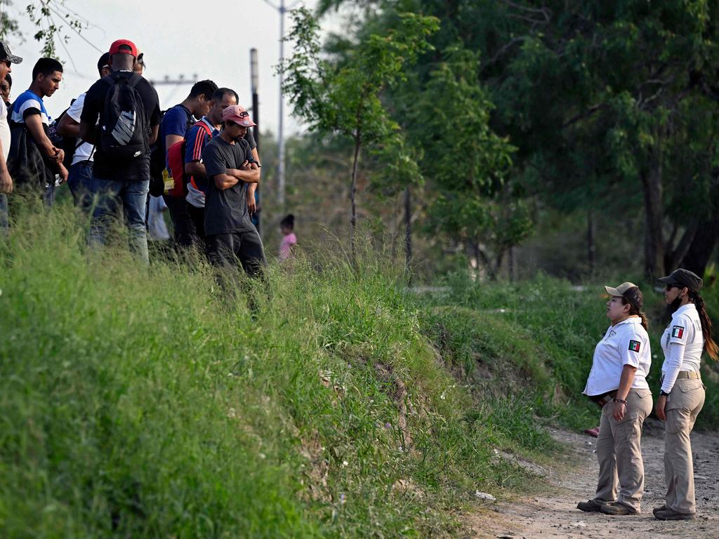 Members of the Beta Group of the Mexican Government instruct migrants not to cross the Rio Bravo river into the US.