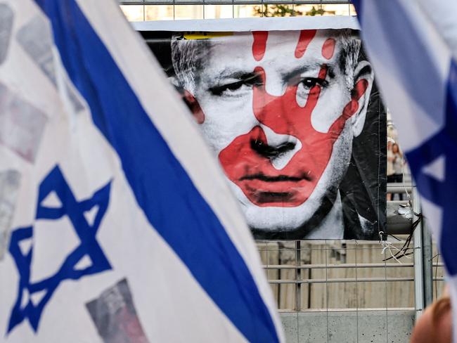 A poster depicting the face of Israeli prime minister Benjamin Netanyahu with a red handprint is pictured between Israeli flags during an anti-government demonstration by left-wing activists in Tel Aviv. Picture: AFP