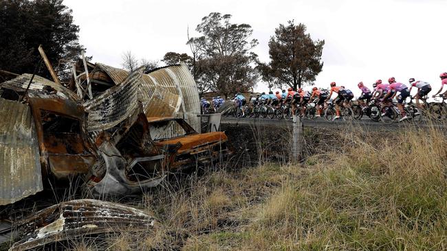 The peloton ride past a burnt out house and cars in Lobethal. Picture: Sarah Reed