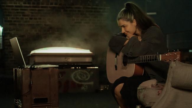 Eve Hewson’s Flora discovers a discarded acoustic guitar in Flora and Son, premiering Friday on Apple TV+.