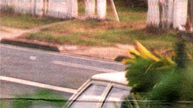 Two gang members shelter behind a car along Barnes Creek Road as shooting breaks out during a bikie war at Cremorne in August 1997. Picture: Lee Constable