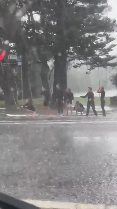 Surfers make the most of Sydneys storm by asking cars for a splash