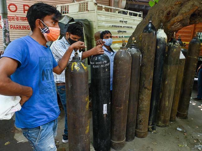 People wait to refill medical oxygen cylinders for coronavirus patients at a private refill centre in New Delhi. Picture: AFP