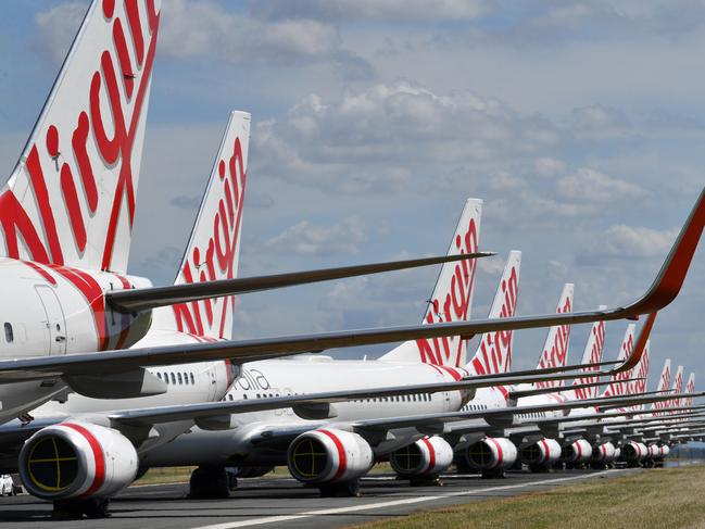 Grounded Virgin Australia aircraft are seen parked at Brisbane Airport in Brisbane, Tuesday, April 7, 2020. Brisbane Airport Corporation (BAC) is working with airlines by accommodating up to 100 grounded aircraft free of charge in response to government-mandated travel restrictions that have grounded a significant proportion of Australia's airline fleet because of the Coronavirus (COVID-19). (AAP Image/Darren England) NO ARCHIVING