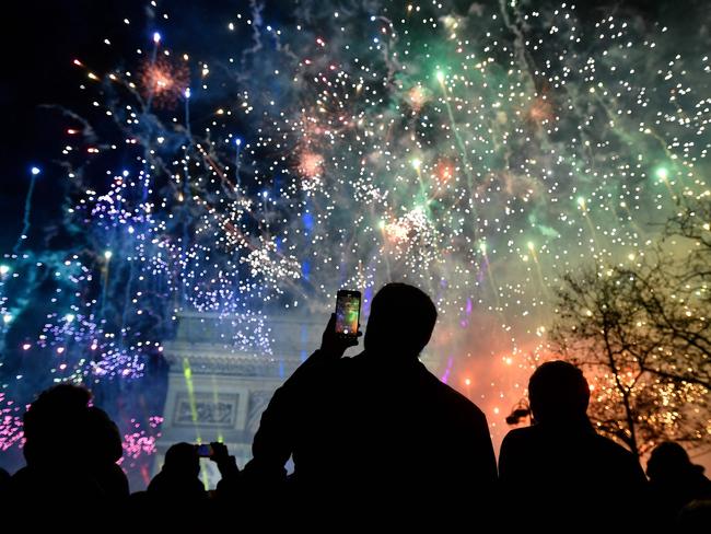 A spectator holds a smartphone as fireworks explode next to the Arc de Triomphe. Picture: AFP