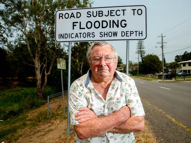 Flood victim Frank Beaumont stands by a flooding sign in Goodna. Picture: Richard Walker