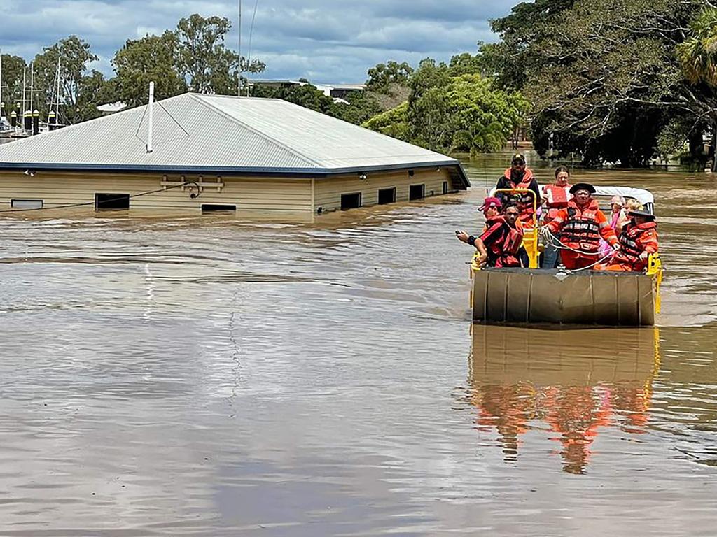 Queensland Fire and Emergency Services rescuers on a boat evacuating people along a flood street around Maryborough in Queensland.