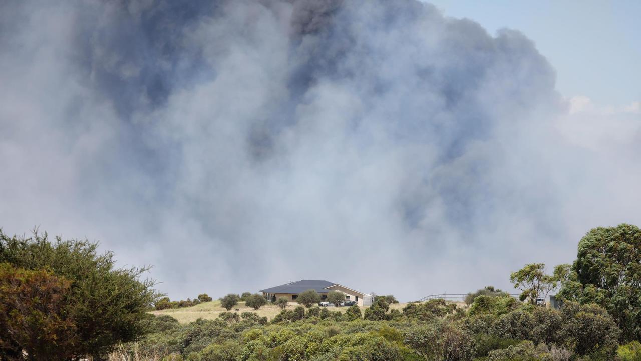 A house is dwarfed against the rising smoke. Picture: Robert Lang