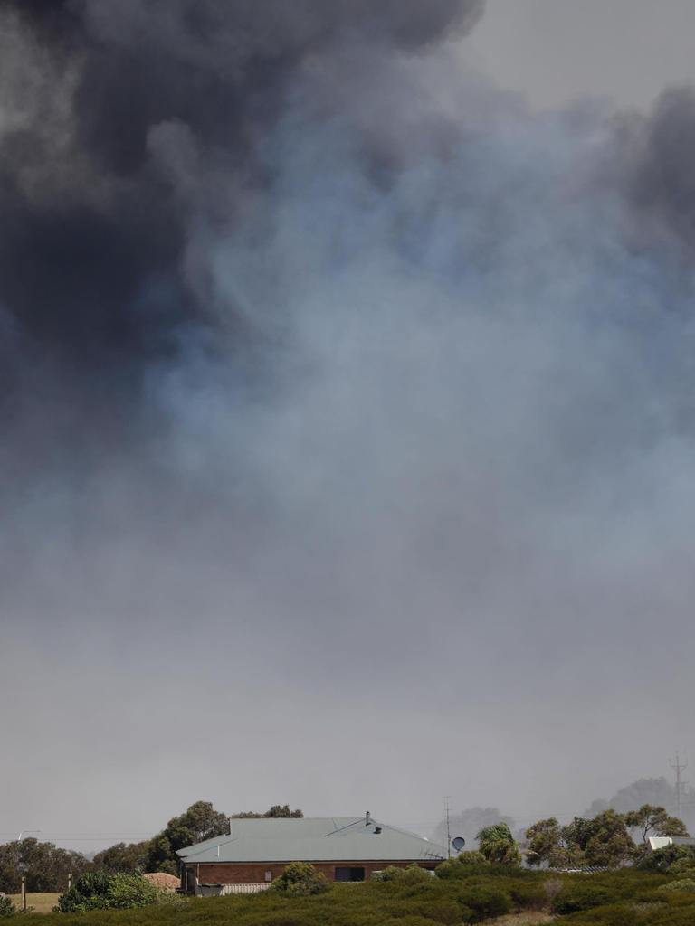 A house is dwarfed against the rising smoke. Picture: Robert Lang