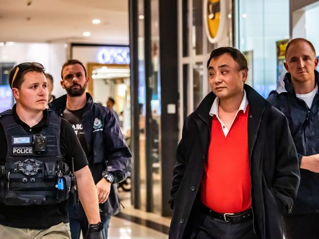 Jin Long Wang is escorted from his Cignall store at Westfield Miranda on July 31. Picture: AAP IMAGE/Monique Harmer