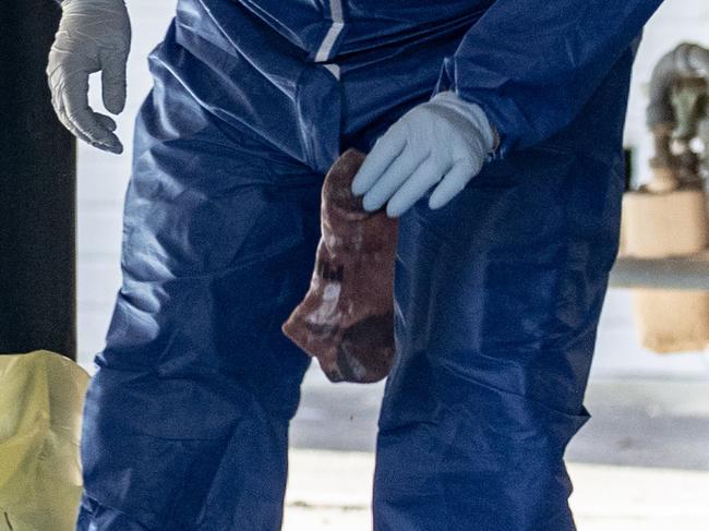 A forensic officer is seen holding a blood-soaked sock. Picture: NCA NewsWire / Dylan Coker