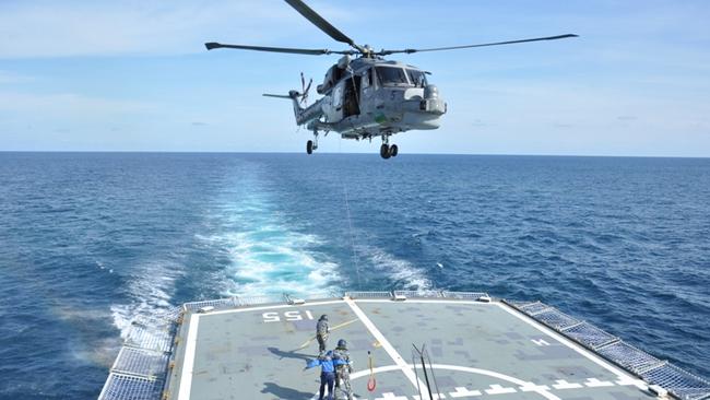 A Malaysian navy helicopter lands on the deck of HMAS Ballarat during exercises in the Strait of Malacca