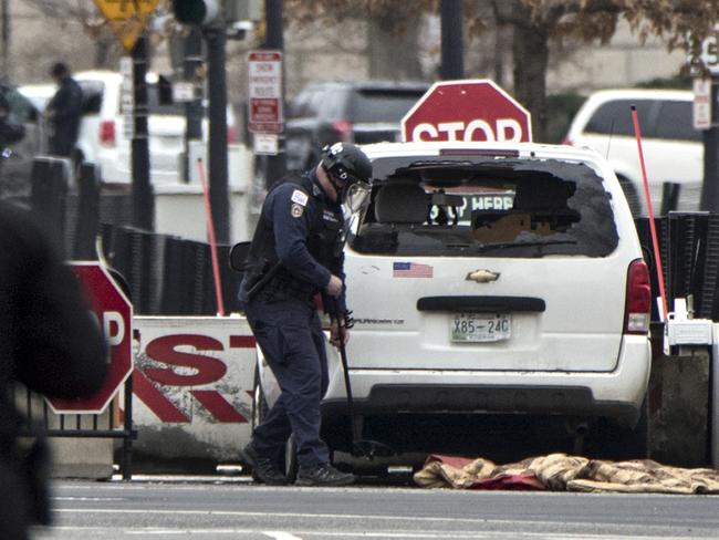 A Secret Service officer checks a white passenger vehicle that struck a security barrier that guards the southwest entrance to the White House grounds. Picture: AP Photo/J Scott Applewhite