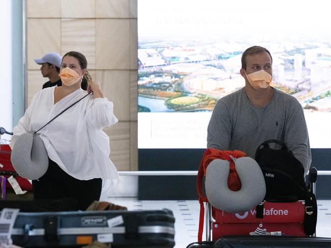 Tourists arrive at Sydney International Airport wearing face masks.