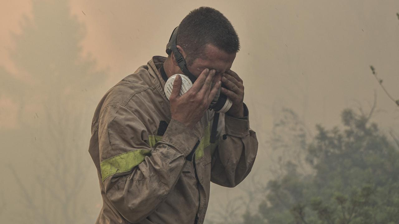 A fireman wipes his eyes as he battles flames burning vegetation while fighting the Prodromos fire. Picture: Spyros Bakalis / AFP