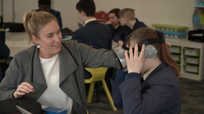 Trinity College maths teacher Hannah Sanders helps year 8 student Mia with a virtual reality headset.