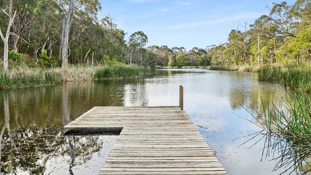 The lake, with a jetty, is surrounded by indigenous Australian reeds and grasses.