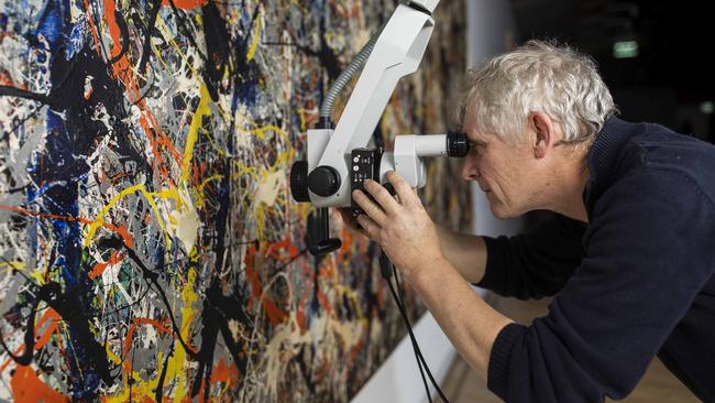 David Wise, Senior Paintings Conservator at the National Gallery of Australia, inspects Jackson Pollock’s Blue Poles. Picture by Sean Davey.