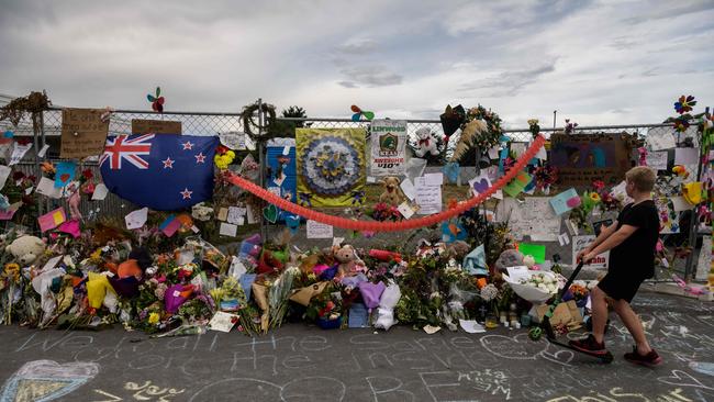 A boy looks at flowers and tributes displayed in memory of the twin mosque massacre victims along the road outside the Linwood mosque (back C) in Christchurch on March 25, 2019. - The slaughter of 50 people at Friday prayers in two Christchurch mosques on March 15 shocked the normally laid-back country and prompted global horror, heightened by the gunman's cold-blooded livestreaming of the massacre. (Photo by ANTHONY WALLACE / AFP)