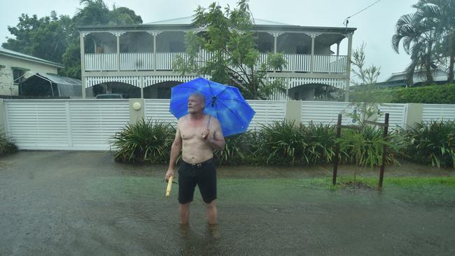 Pimlico resident John McGuire tries to get cars to slow down in the flooded road outside his home in Palmerston Street. Picture: Evan Morgan