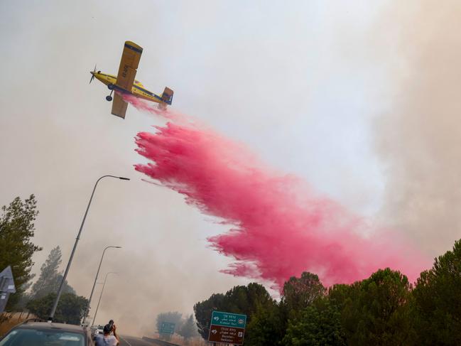 TOPSHOT - An Israeli firefighter airplane drops flame retardant on fires smoke after rockets launched from southern Lebanon hit areas in northern Israel on July 4, 2024. Lebanon's Hezbollah said it launched more than 200 rockets and explosive drones at Israeli military positions on July 4 as tensions have soared amid the almost nine-months-old war raging in Gaza. (Photo by Jalaa MAREY / AFP)