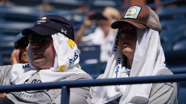 Fans shield from the sun as they watch Novak Djokovic of Serbia against Marton Fucsovics of Hungary. Picture: AFP