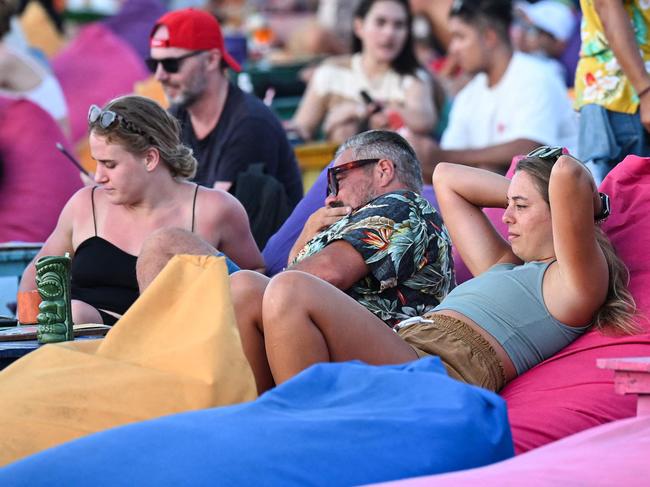 Foreign tourists relax on the Kuta Beach near Denpasar on Indonesia's resort island of Bali on November 18, 2023. (Photo by SONNY TUMBELAKA / AFP)