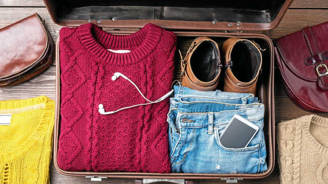 Open suitcase with casual female winter clothes on wooden table. Top view. Picture: LeszekCzerwonka