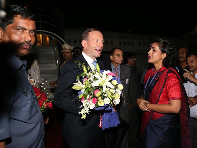 Tony Abbott is presented with flowers as he arrives in Mumbai.
