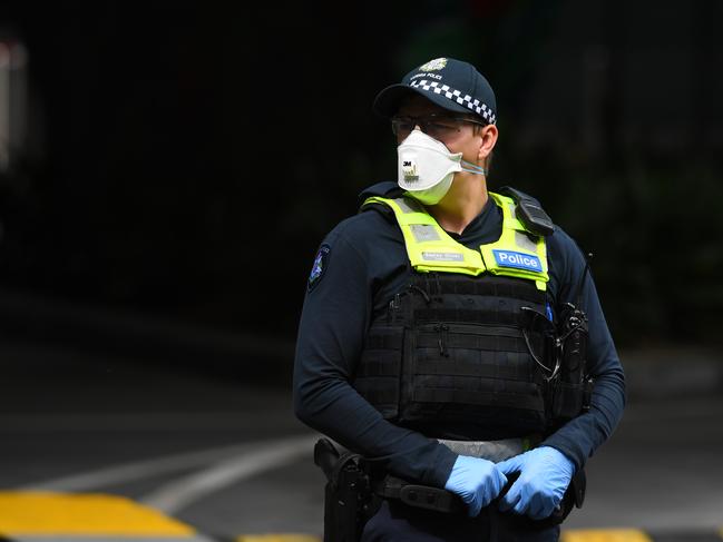 A Victorian Police officer wearing a face mask is seen outside of Crown Metropol Hotel in Melbourne, Monday, March 30, 2020. Travellers and Australian residents who arrive into the country from overseas are being sent straight to makeshift quarantine facilities across Australia. Travellers will spend 14 days of quarantine in state-funded hotel rooms, with doors guarded by state police, defence personnel or private security guards.(AAP Image/Bianca De Marchi) NO ARCHIVING