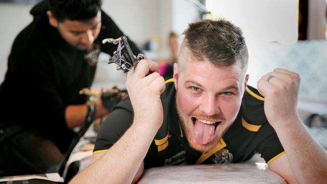 Ryan Wilhelm looks pretty happy with himself as Dusty gets inked on his rear. Picture: Danella Bevis