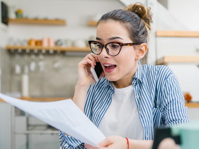 Upset woman talking on mobile phone and doing paper work