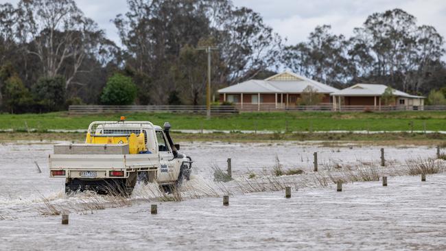 Flooding around the Macalister River flowing out of Lake Glenmaggie. A farmer drives through their flood water. Picture: Jason Edwards