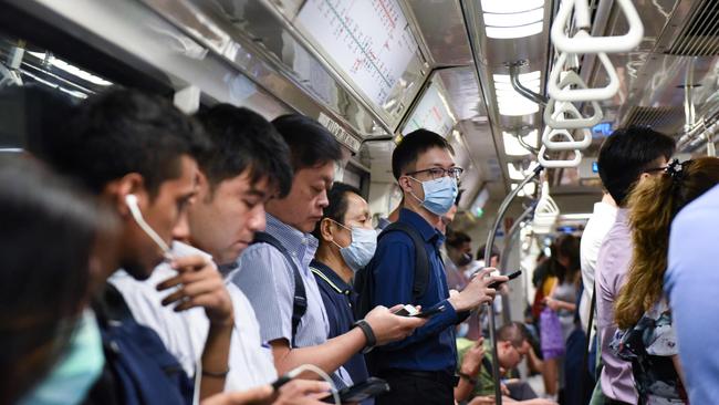 Commuters wear face masks on Singapore’s Mass Rapid Transit train. The island nation leads the world in containing the disease, due largely to the people’s trust in their government. Picture: AFP