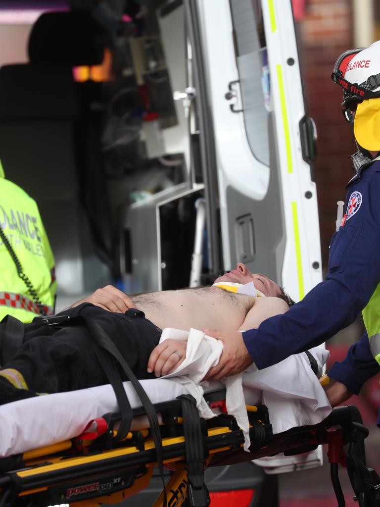 An firefighter injured at South Turramurra is assisted by ambulance officers. Picture: John Grainger