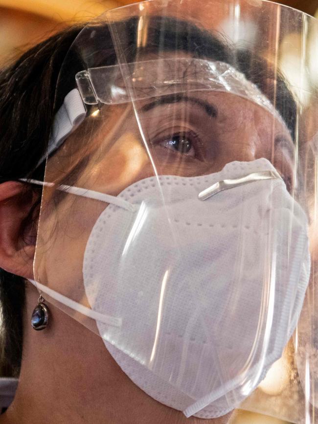 A woman wearing a face mask and shield attends a mass at the Basilica de los Angeles in Cartago, Costa Rica, June 28, 2020, amid the new coronavirus pandemic. - The third phase of measures against the spread of COVID-19 began Sunday in Costa Rica, allowing assistance to churches with a minimum distance of 1.8 meters between each person and with a maximum of 75 people, all with masks. (Photo by Ezequiel BECERRA / AFP)