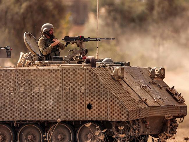 An Israeli army soldier puts on his helmet as he mans a turret in an armoured tracked vehicle deployed at a position along the border with the Gaza Strip in southern Israel. Picture: AFP