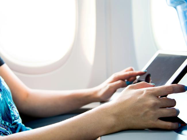 Woman using digital tablet on airplane.