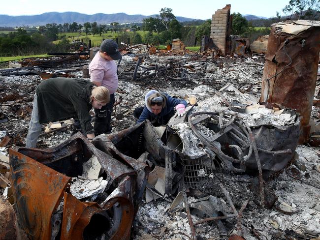 Rebecca Sloane and her kids Alex and Jack sift through the remains of their burnt down home. Picture: Toby Zerna