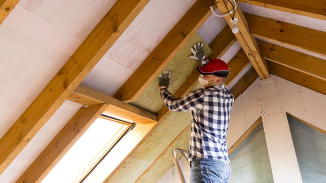 Man installing thermal roof insulation layer - using mineral wool panels. Attic renovation and insulation concept