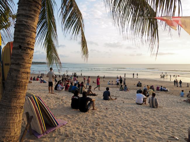 Sunset at Kuta Beach in Bali. Many people can be seen sitting on the beach watching the last rays of light before the sun descends for another day. Picture: iStock