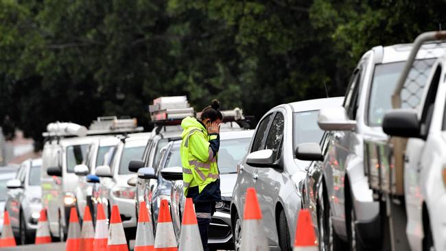 A traffic warden manages a queue of cars outside a drive-through Covid-19 testing clinic in Sydney's Fairfield. Picture: AFP