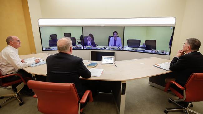 Secretary of the Department of Prime Minister and Cabinet, Phil Gaetjens, Prime Minister Scott Morrison and Chief Medical Officer Professor Brendan Murphy, speak with Queensland Premier Annastacia Palaszczuk (on screen) during a National Cabinet meeting to discuss COVID-19 (coronavirus), from the teleprescence room of Parliament House in Canberra on Sunday 22 March 2020. Photo: Alex Ellinghausen.