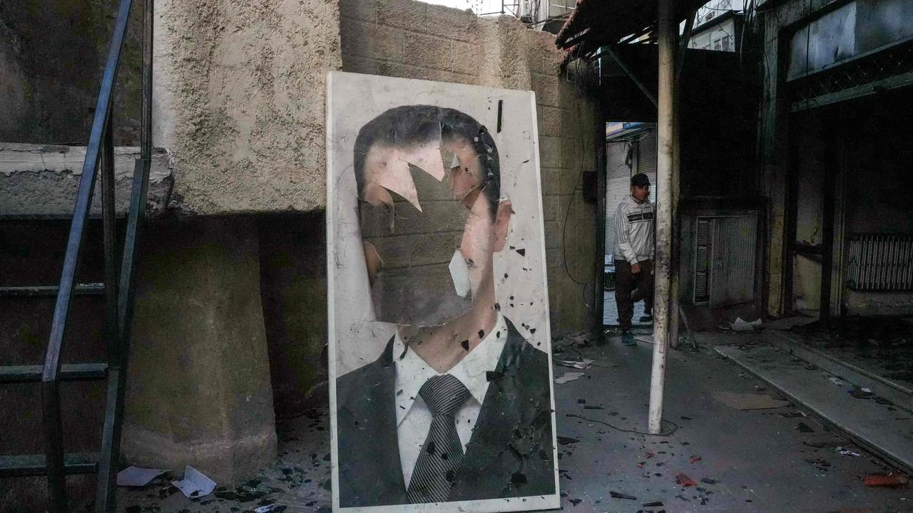 A defaced portrait of ousted Syrian president Bashar al-Assad stands in a ransacked government security facility, in Damascus, on December 8, 2024. (Photo by Rami al SAYED / AFP)