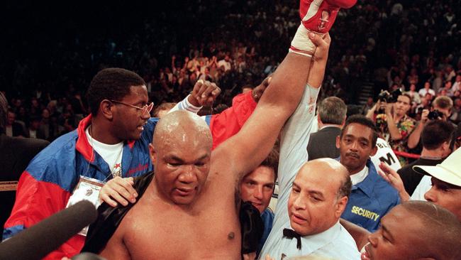 Referee Joe Cortez (R) holds George Foreman's arm up in victory after Foreman knocked Michael Moorer out in the tenth round. Photo by JOHN GURZINSKI / AFP.