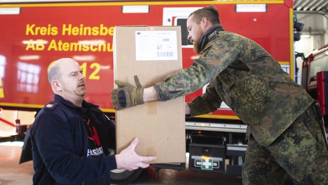 German soldiers and firefighters load boxes of protective clothes in Erkelenz, Germany, to be sent to Heinsberg district. Picture: Jonas Guettler/AP