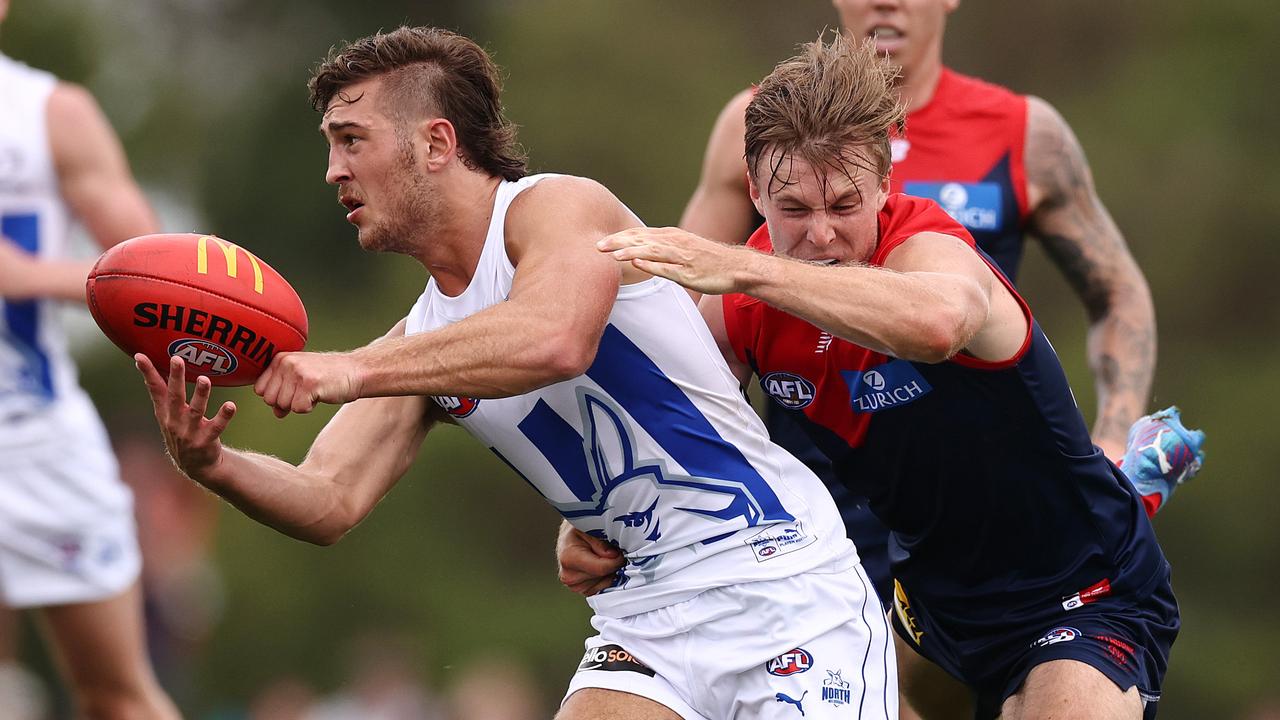 North Melbourne’s Will Phillips gets a handball away under heat from Melbourne during a practice match at Casey Fields in February 2022. Picture: Michael Klein